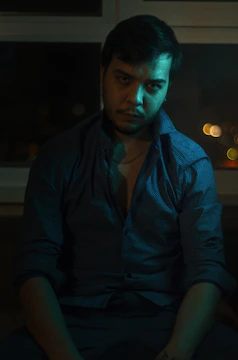 A cinematic still from Eduardo del Llano's latest film project showing a thoughtful character in a dimly lit room.