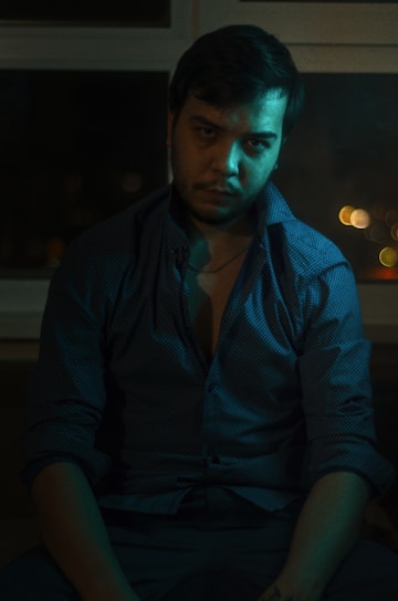 A focused man sitting calmly in a minimalist room, reflecting strength and emotional control.