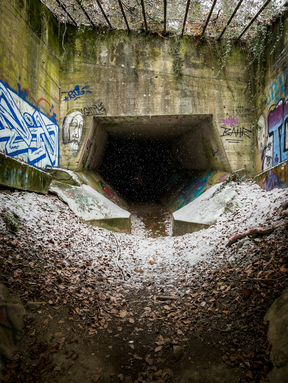 a concrete tunnel with graffiti on the walls