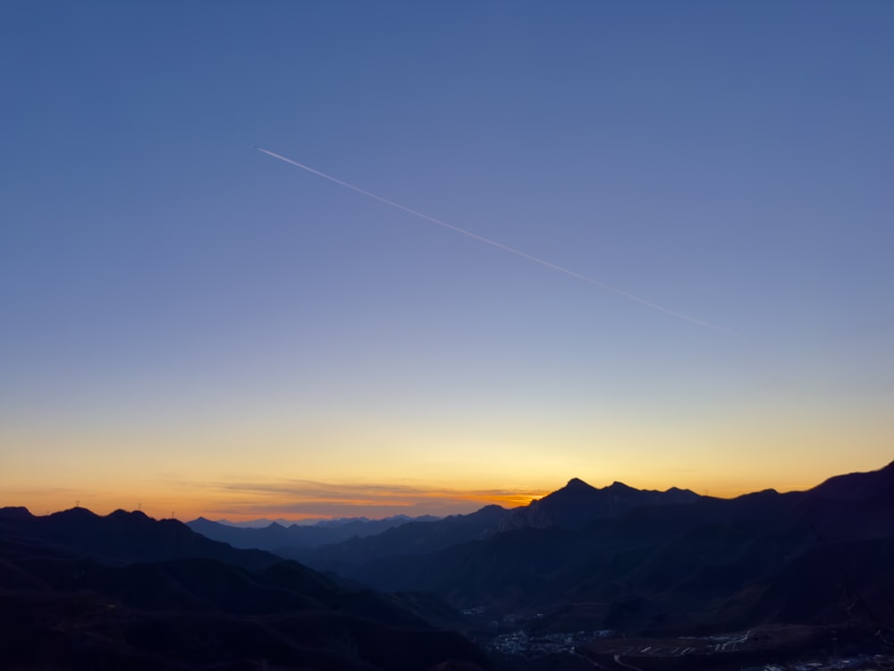 the sun is setting over a mountain range