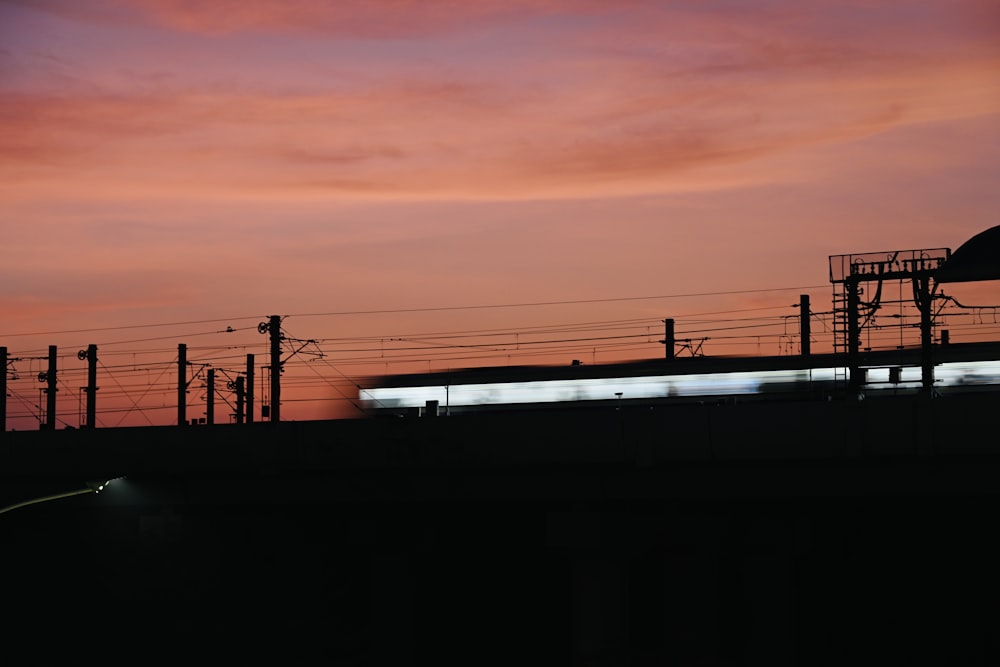a train traveling past a train station under a pink sky