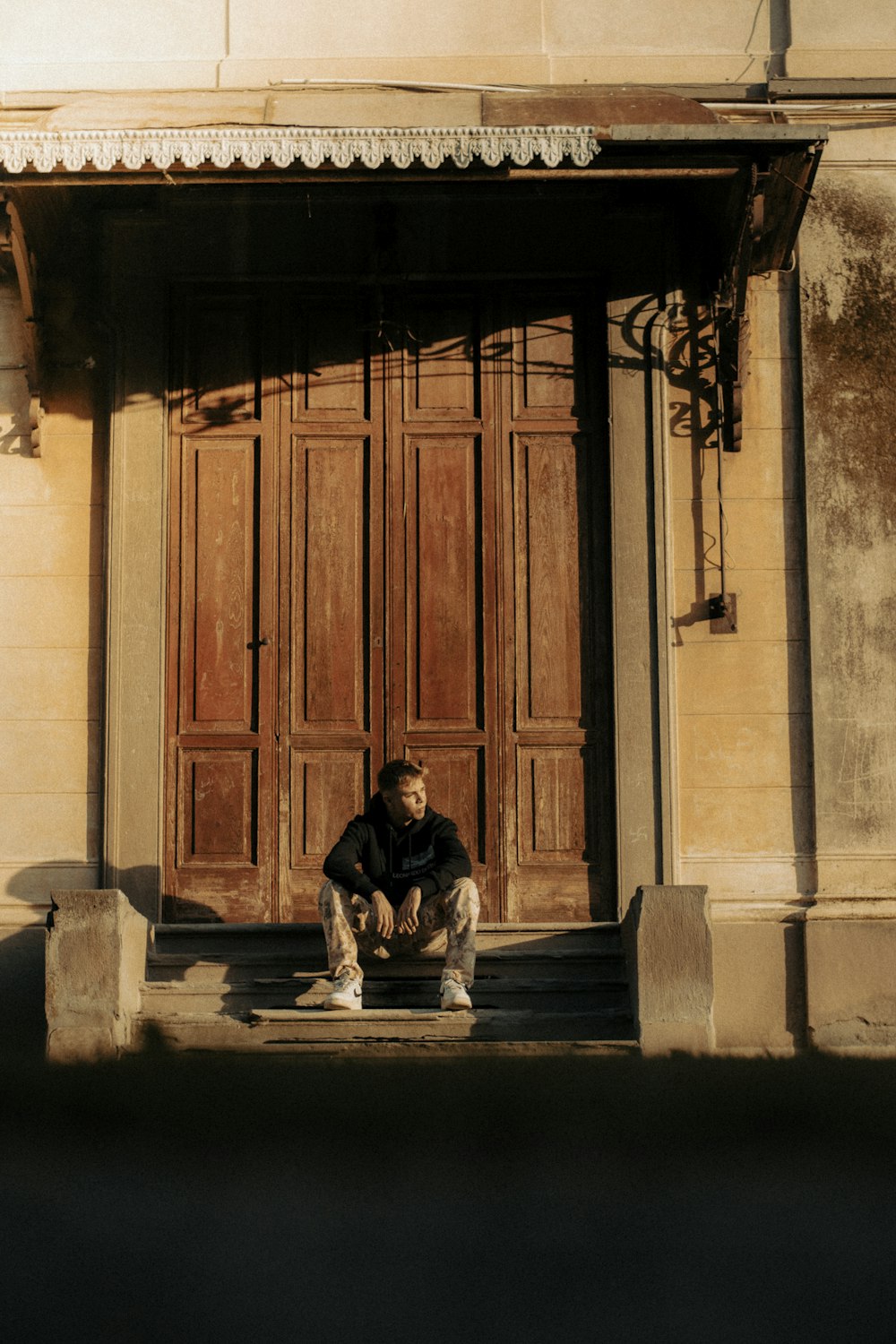 Un homme assis sur une marche devant un immeuble