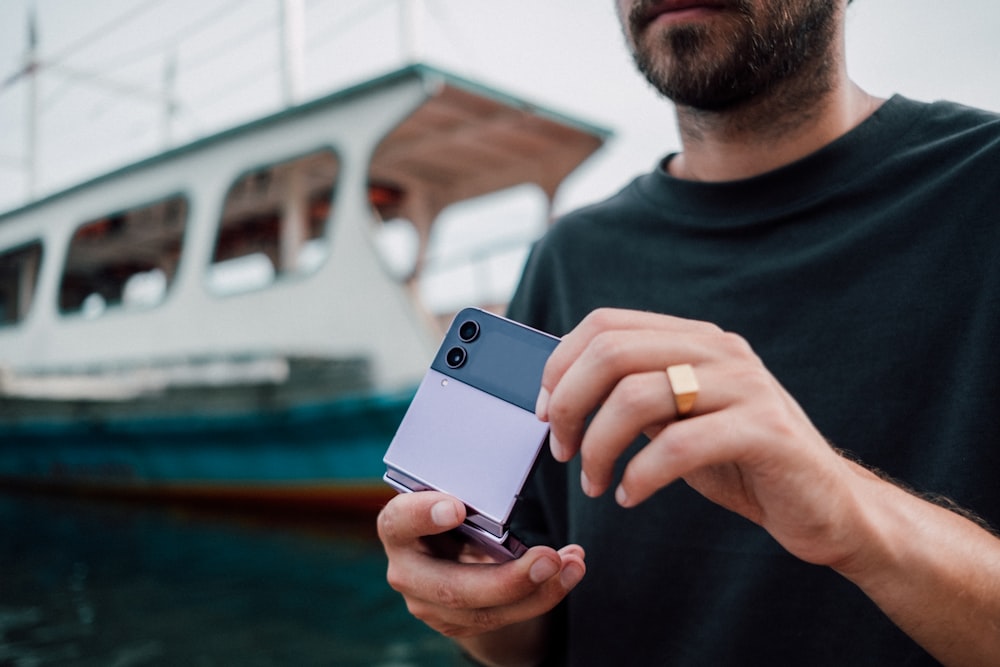 um homem segurando um telefone celular na frente de um barco