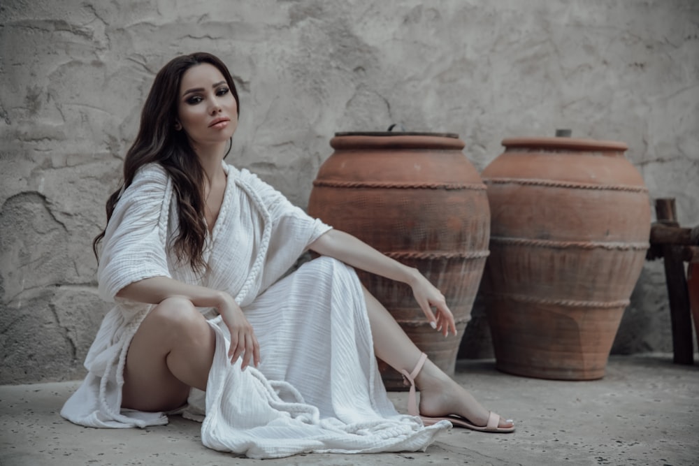 a woman sitting on the ground next to two large vases