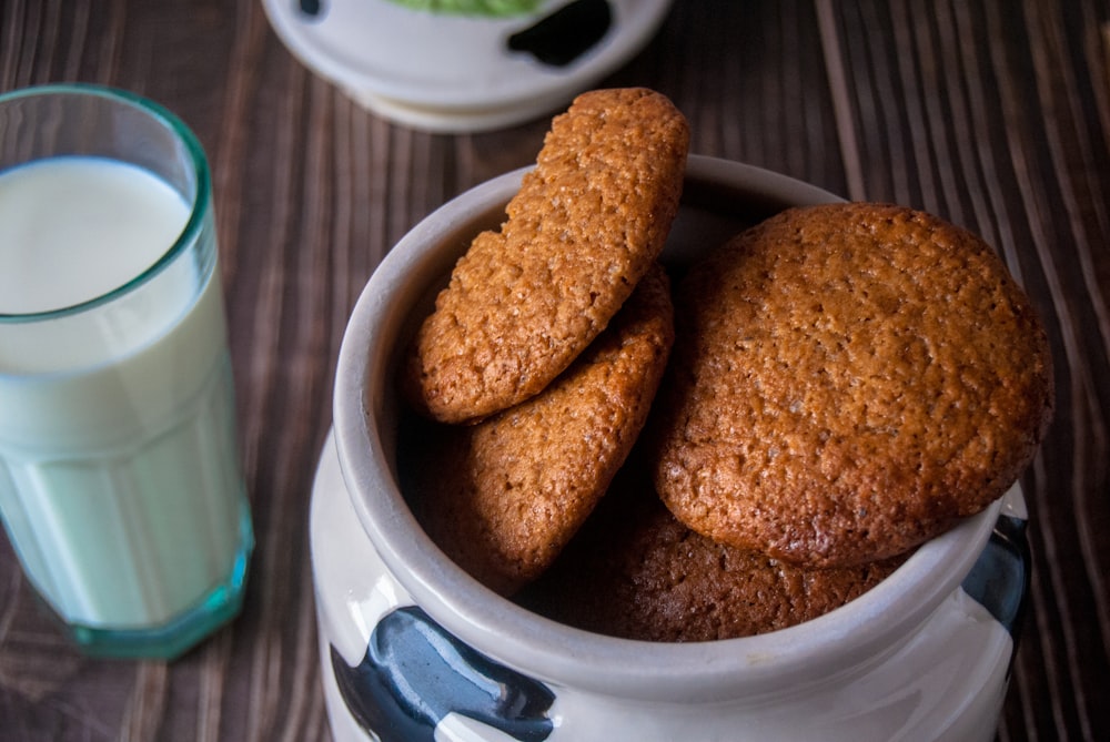 a bowl of cookies next to a glass of milk