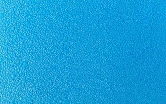 Blue surface covered with small water droplets creating a textured appearance.