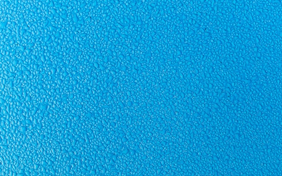 Blue surface covered with small water droplets creating a textured appearance.