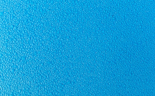 Blue surface covered with small water droplets creating a textured appearance.