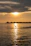 A serene sunset over the turquoise waters of the Maldives with a luxury overwater villa in the foreground.