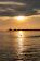 A serene overwater villa at sunset with turquoise waters reflecting the sky.