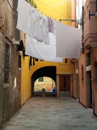 A narrow alley in the Philippines, where colorful laundry hangs above and sunlight filters through.