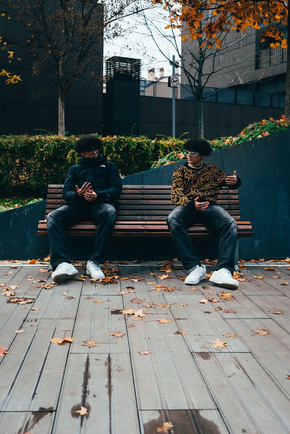two men sitting on a bench in a park
