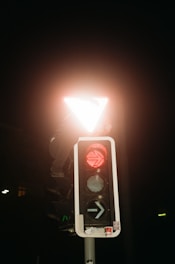 A bright safety orange arrow board mounted on a truck, glowing vividly against a dusk sky.