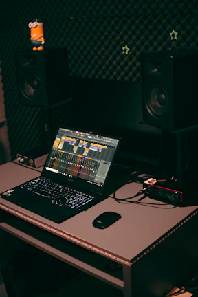 A cozy home studio setup with a microphone, headphones, and a laptop