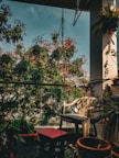 A peaceful balcony with comfortable seating surrounded by lush greenery.