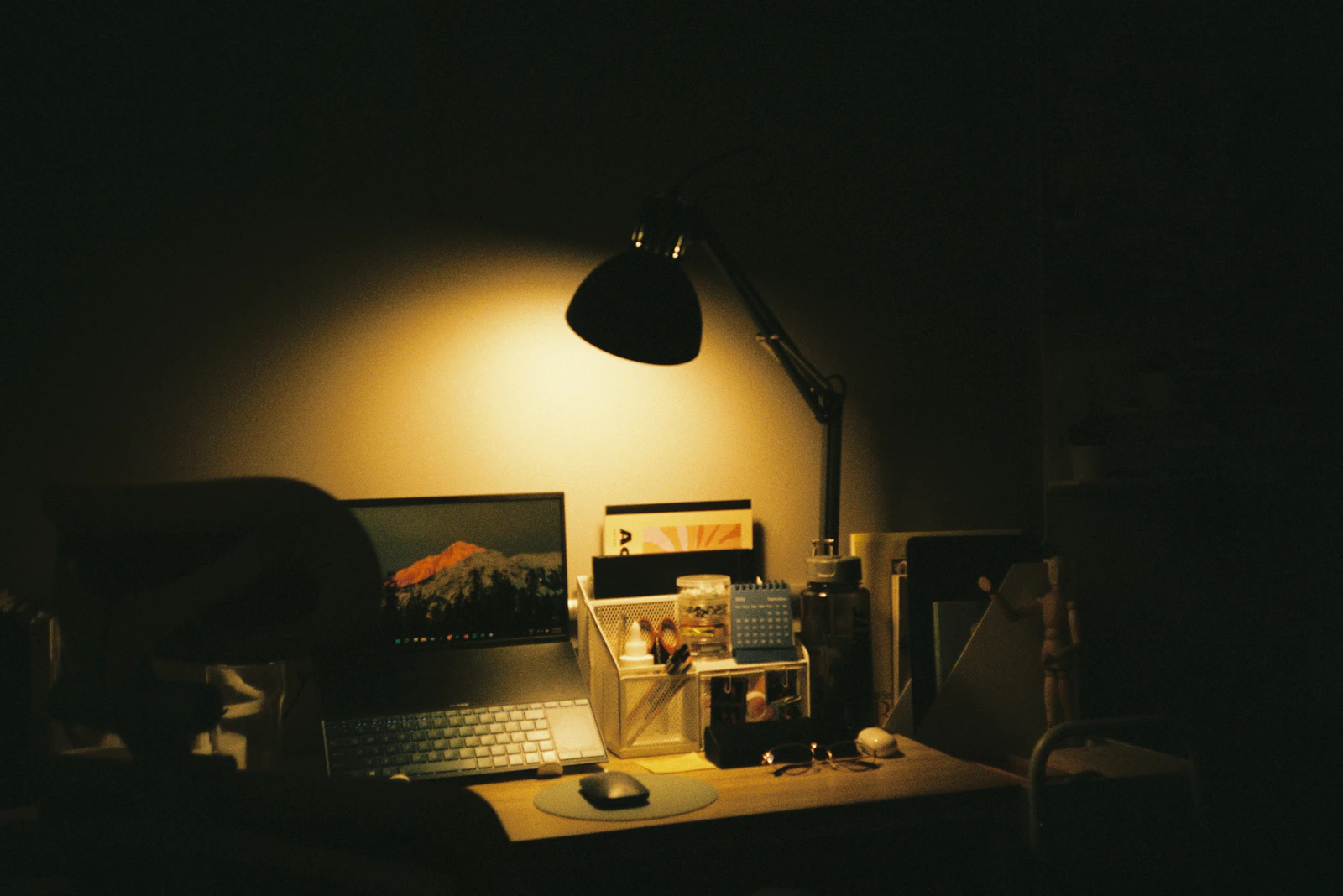 Minimal laptop workspace illuminated by a warm focused desk lamp