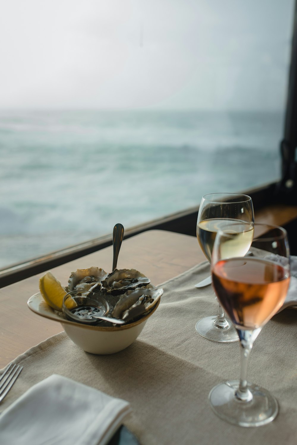 a bowl of oysters and a glass of wine on a table