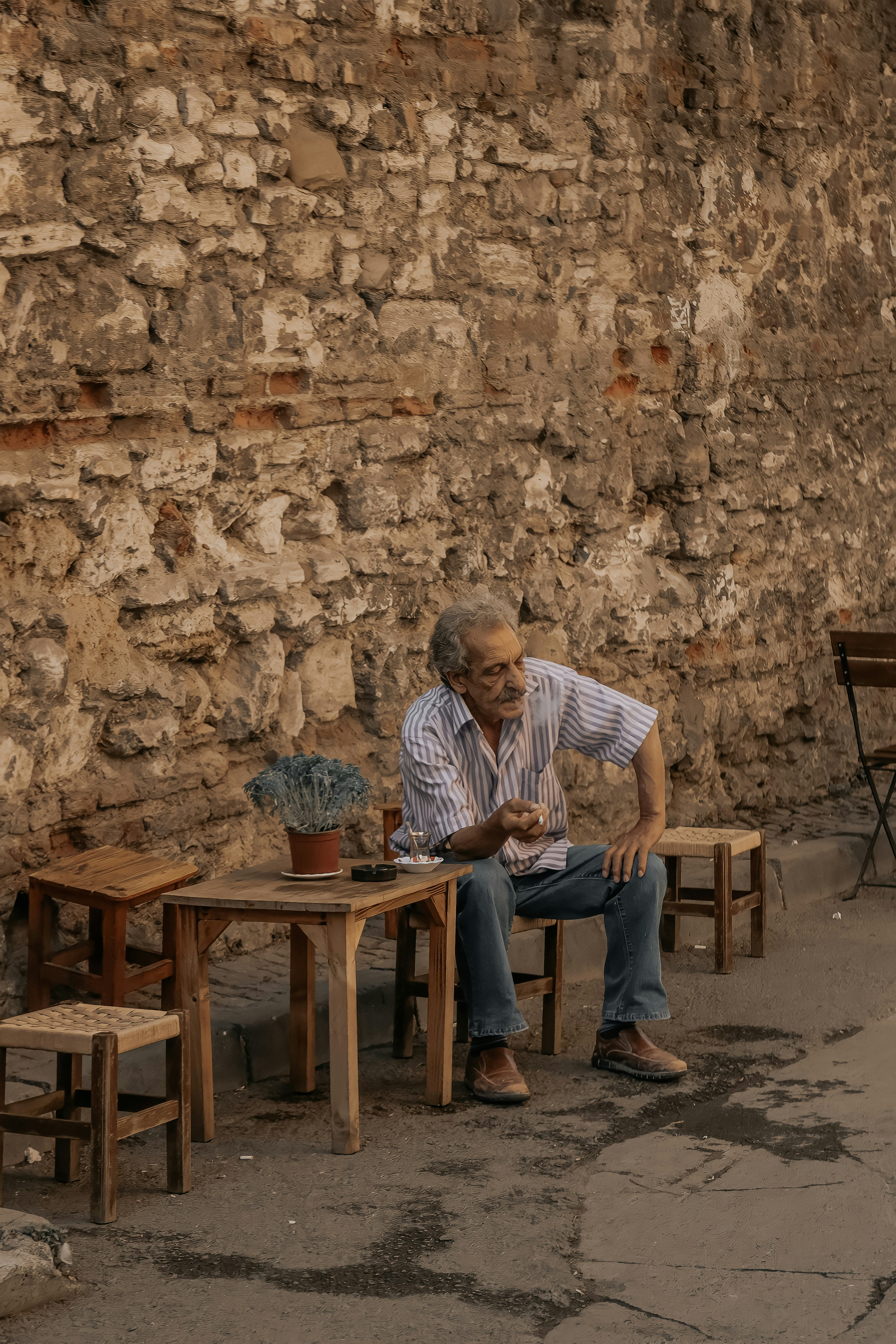 Ein Mann sitzt auf einer Bank vor einer Steinmauer