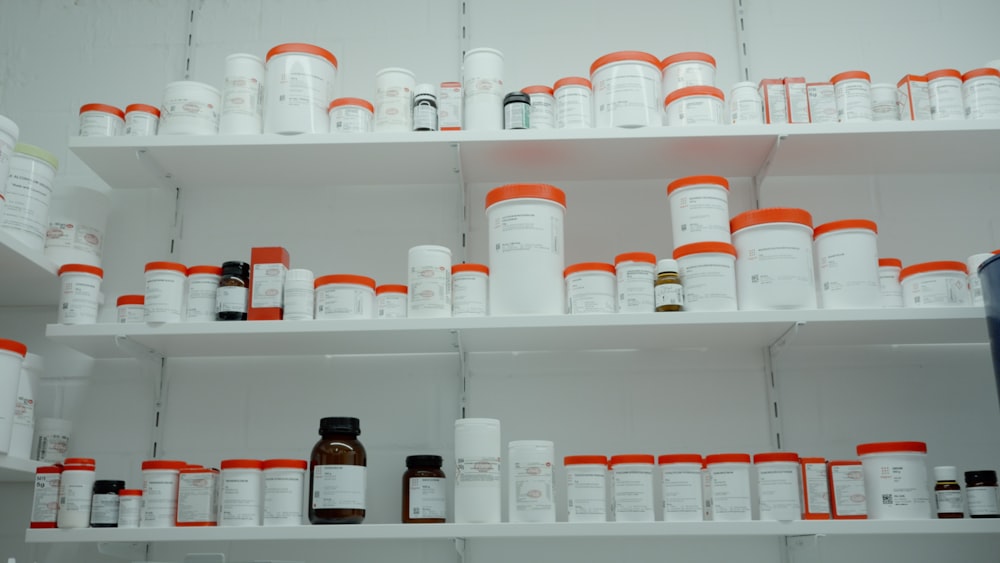 a shelf filled with lots of white and orange medicine bottles