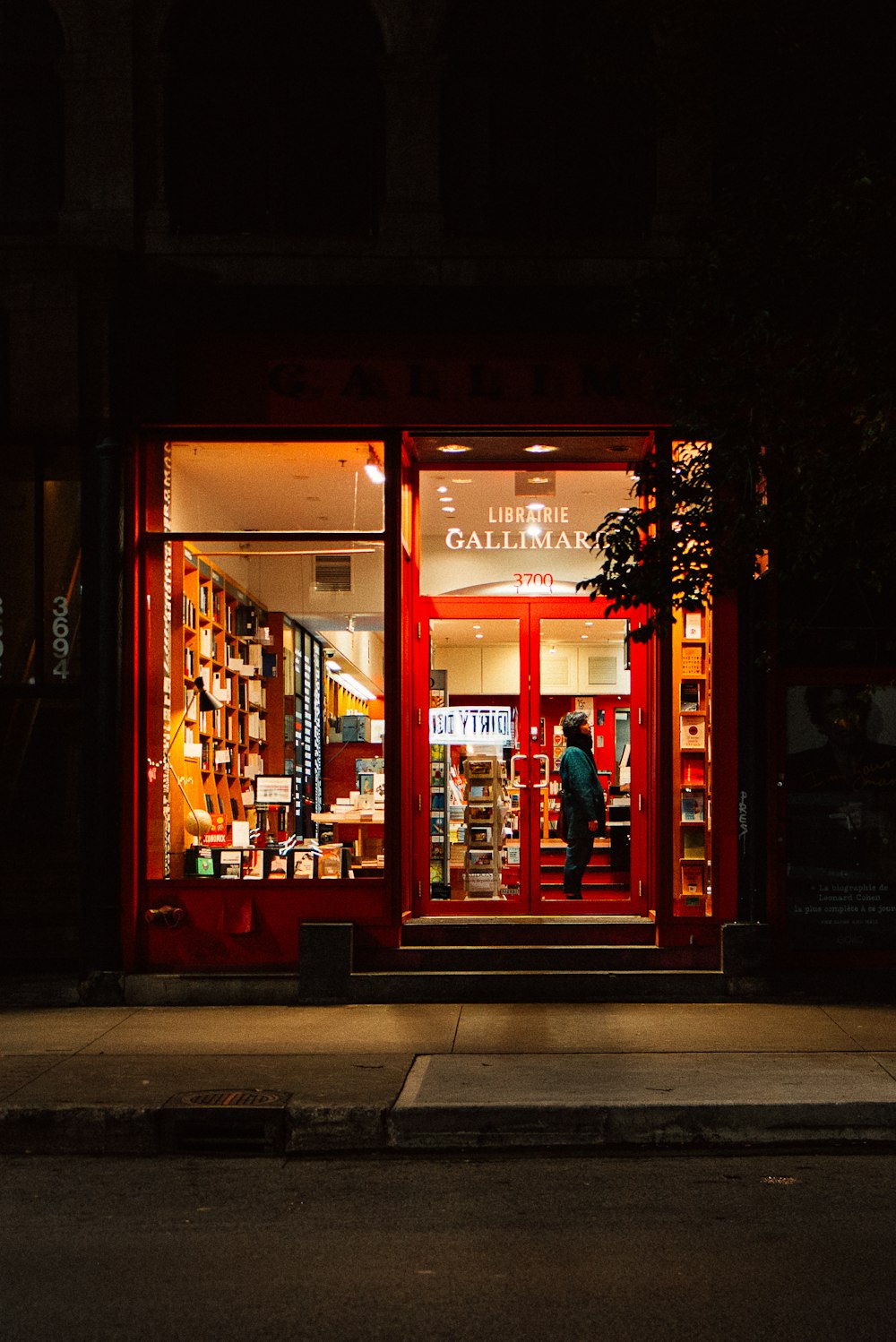 a store front at night with a person walking in the doorway