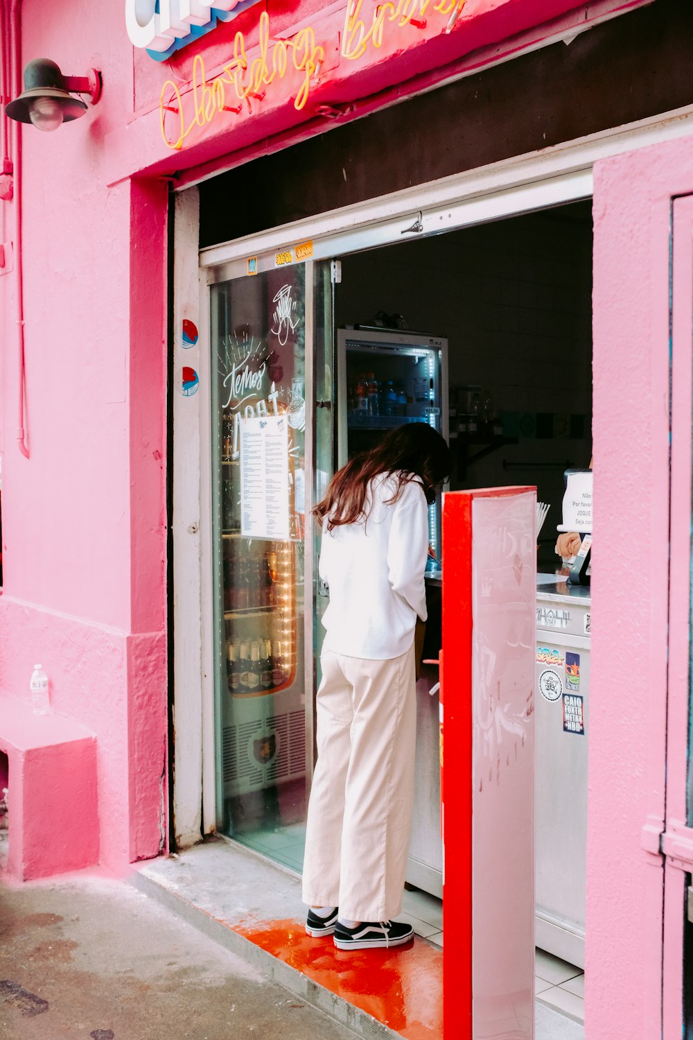 a woman standing at the door of a pink store