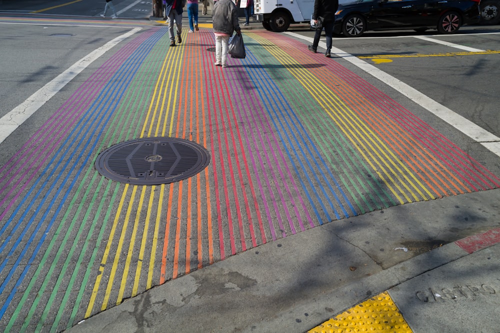 a manhole cover painted in rainbow colors on a city street