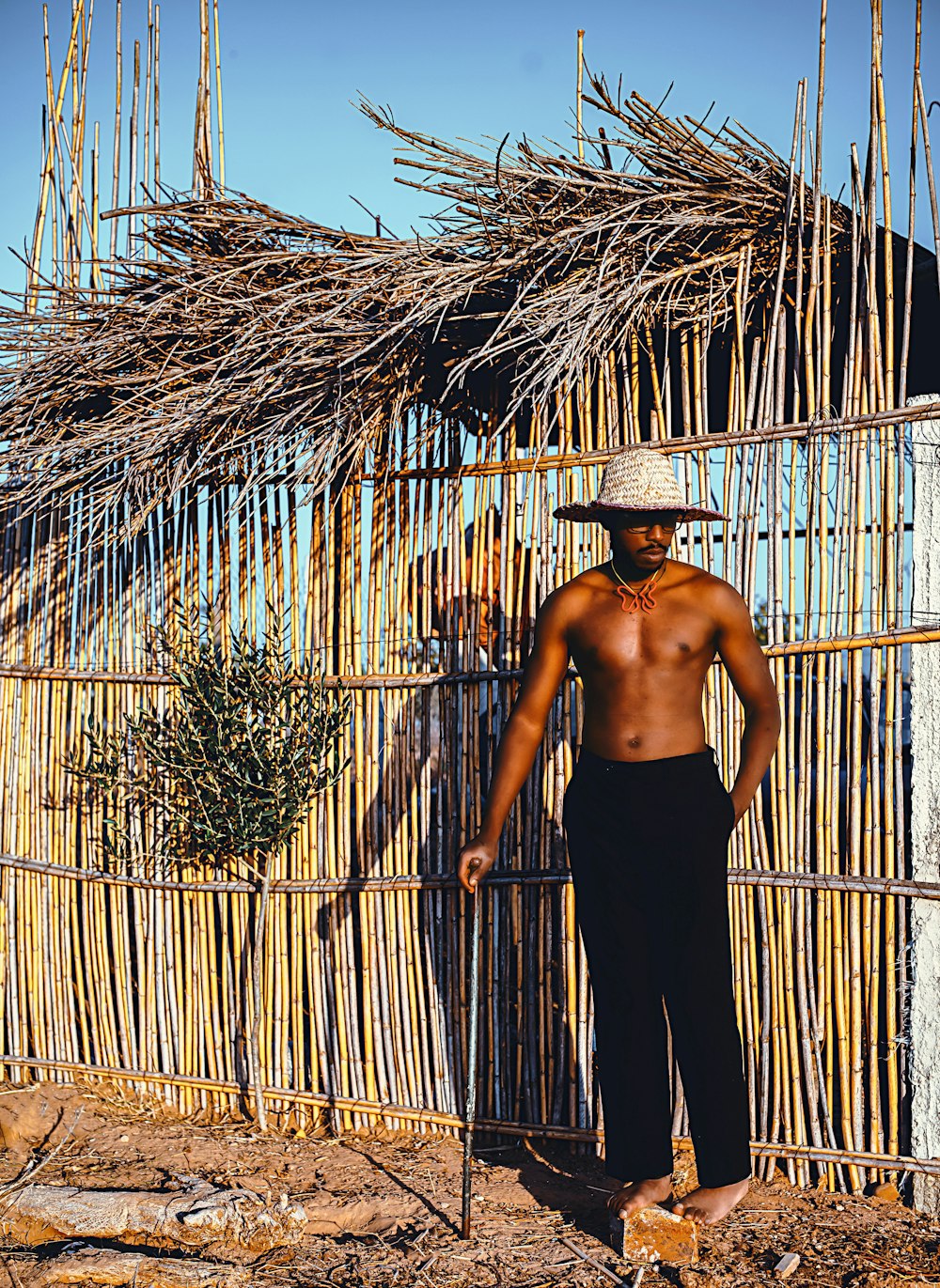 a man standing in front of a bamboo fence