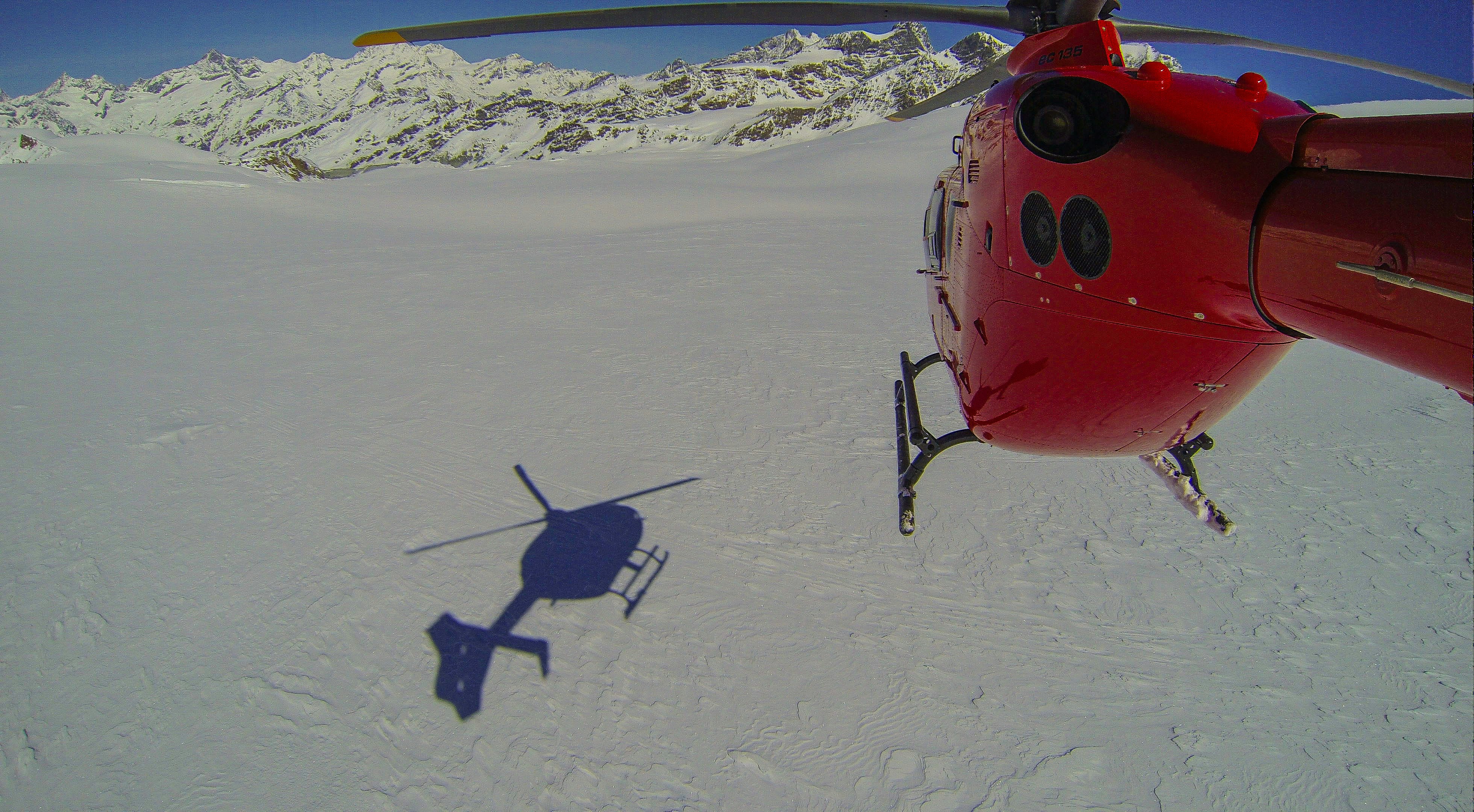 a helicopter flying over a snow covered mountain