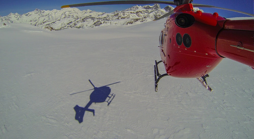 a helicopter flying over a snow covered mountain