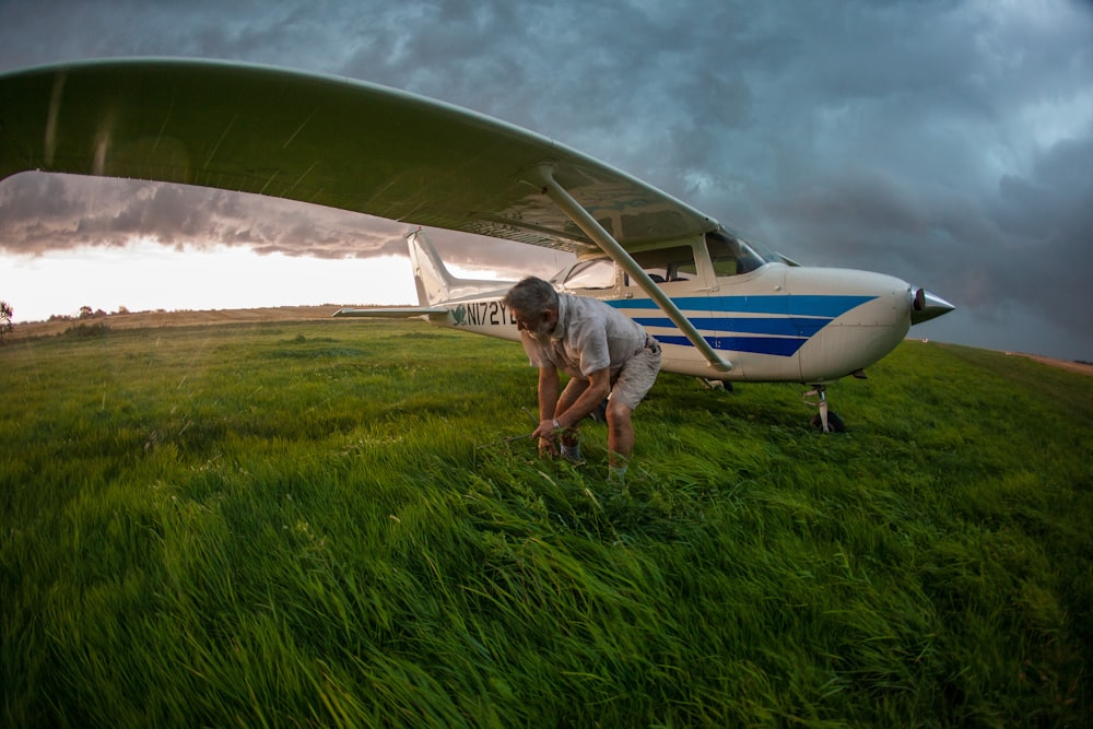 a man standing next to an airplane on a lush green field