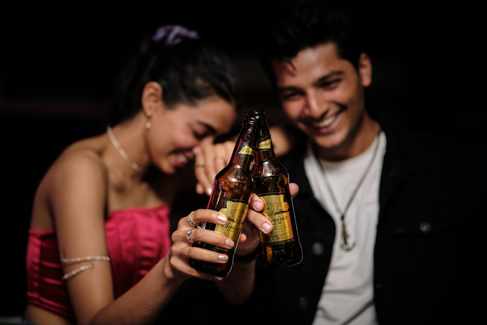 a man holding a beer bottle next to a woman