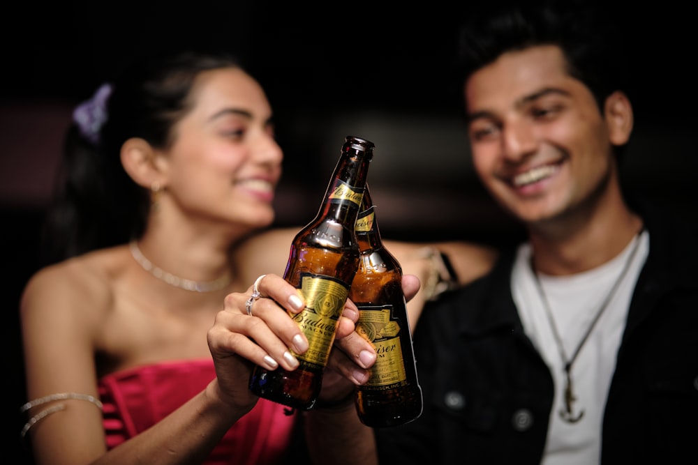 a man holding a beer bottle next to a woman