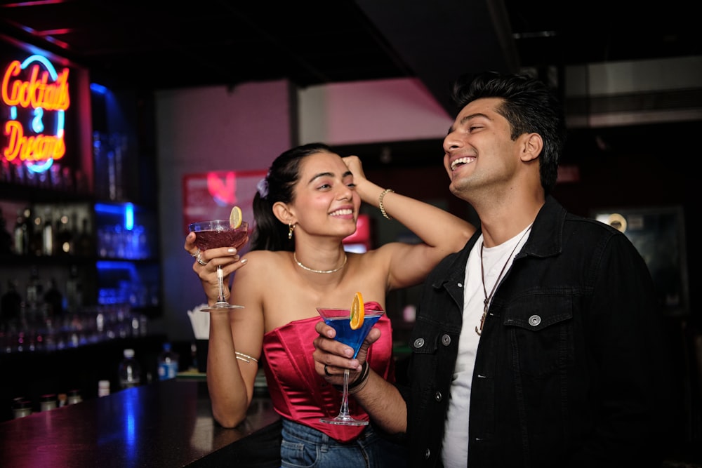 a man standing next to a woman holding a wine glass