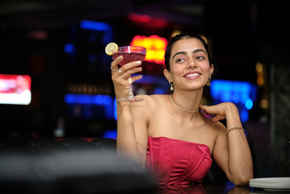 a woman in a red dress holding a drink