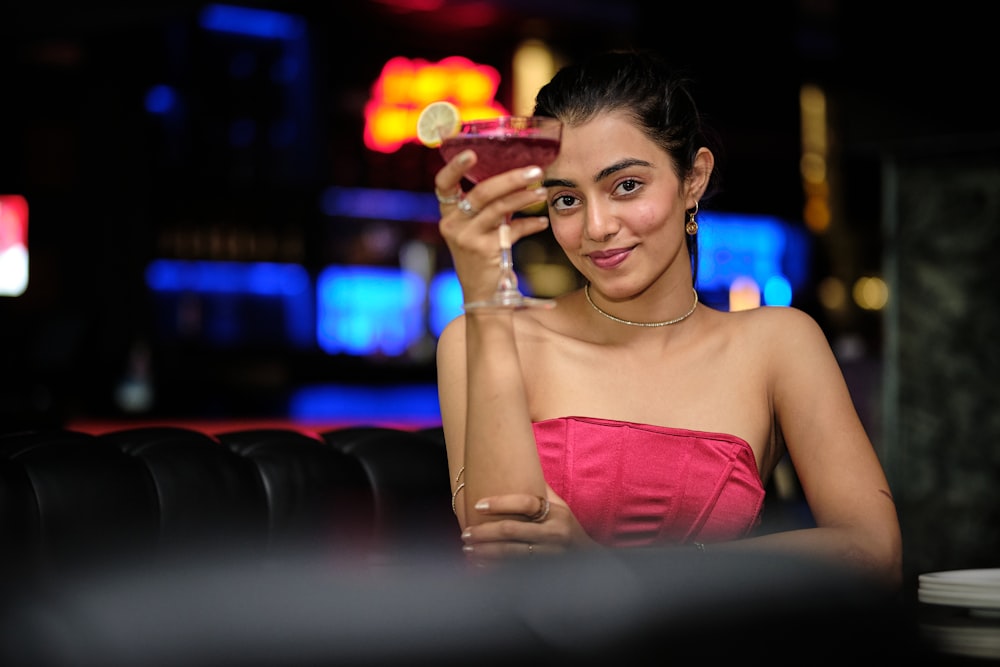 a woman sitting at a table holding a drink