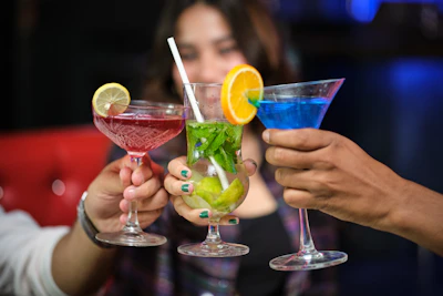 Close-up of hands clinking colorful drinks in a cheerful toast.
