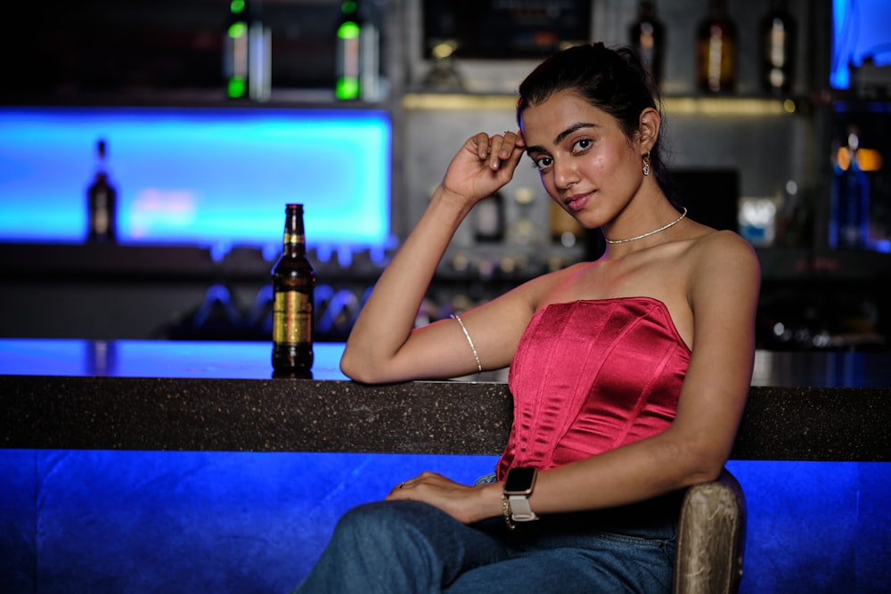 a woman sitting at a bar with a bottle of beer