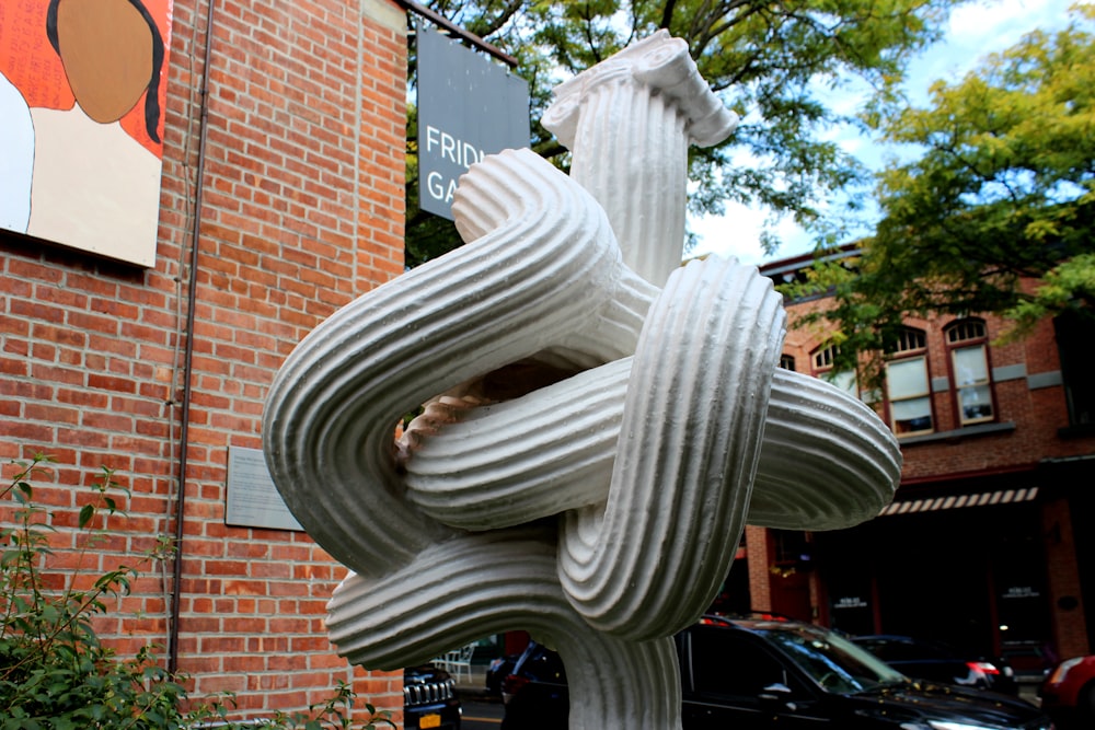 une sculpture d’un nœud sur un poteau devant un bâtiment en briques