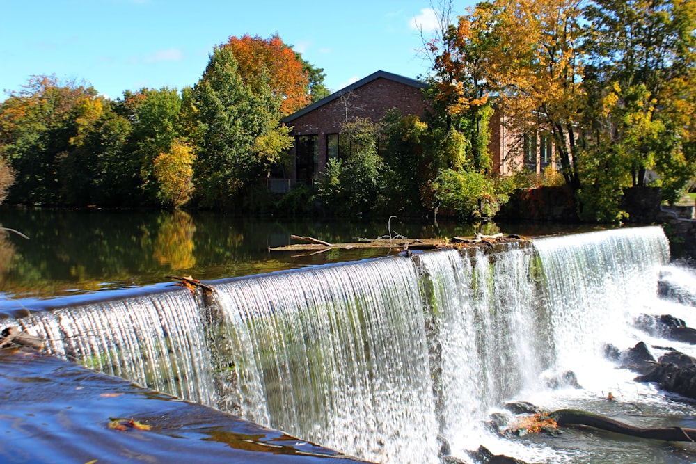 a large waterfall with a house in the background