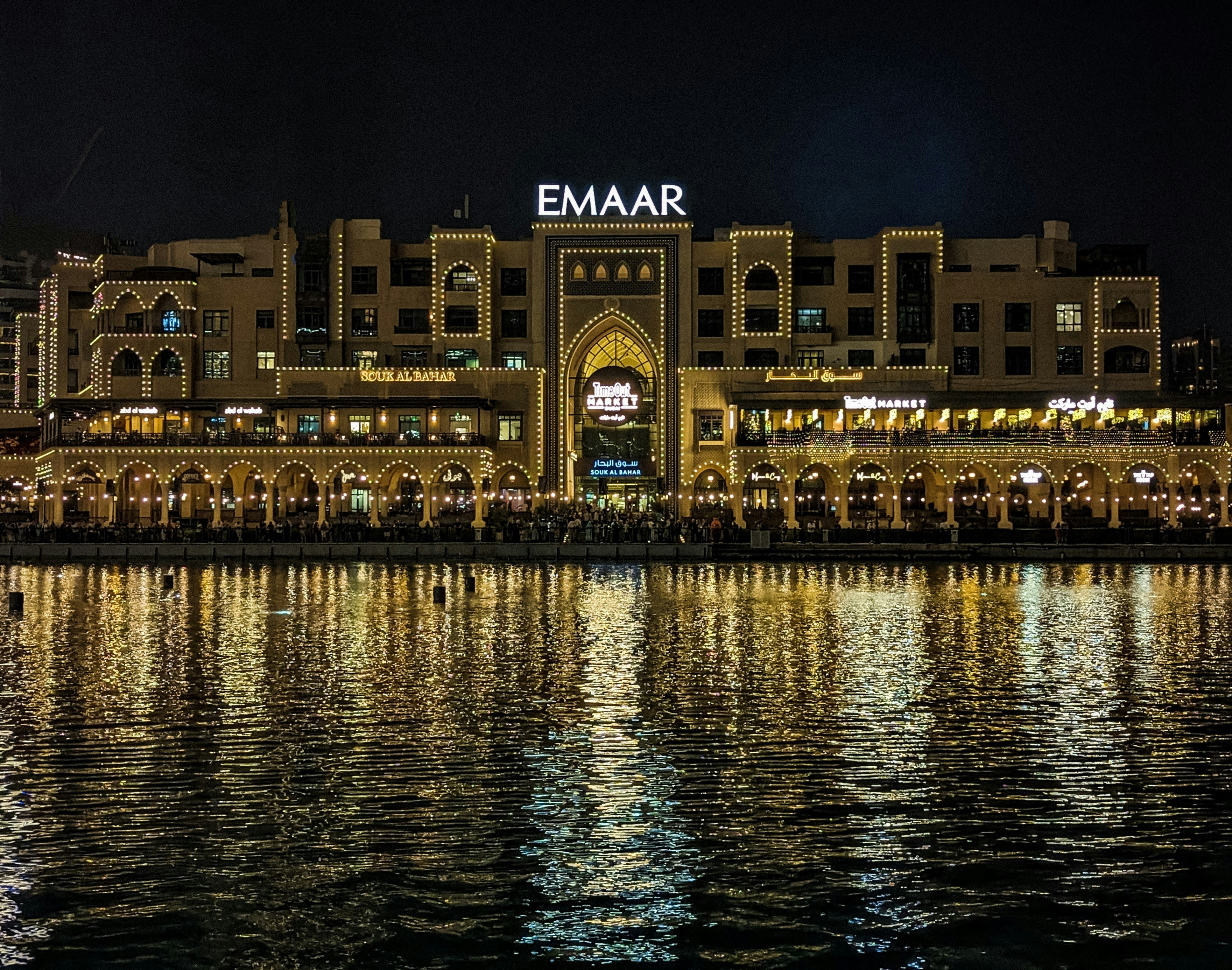 Dubai Creek Harbour luxury apartment at night, illuminated towers, dark water reflections, premium residential
