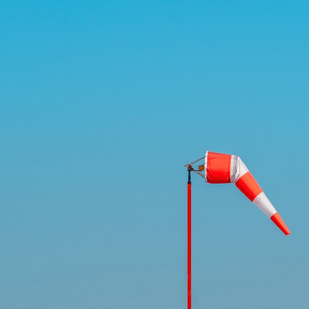 a red and white flag on a pole with a blue sky in the background