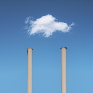 two smoke stacks with a cloud in the sky