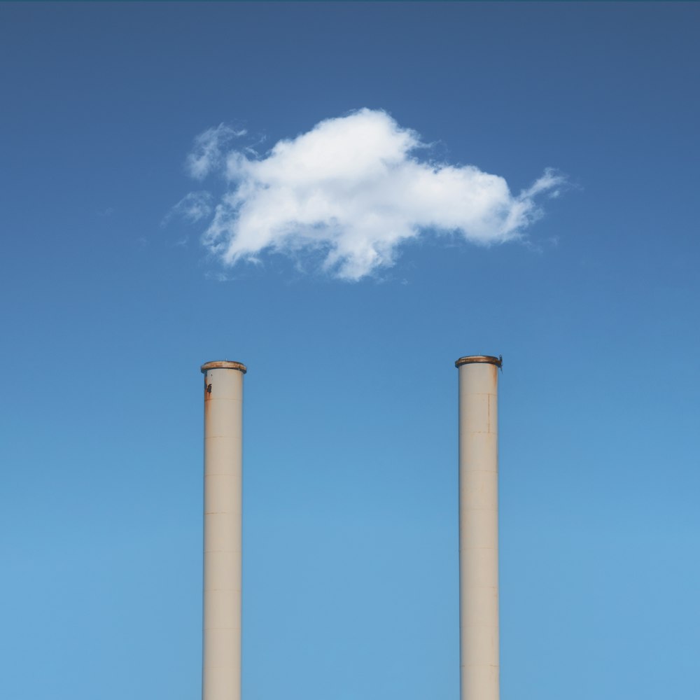 two smoke stacks with a cloud in the sky