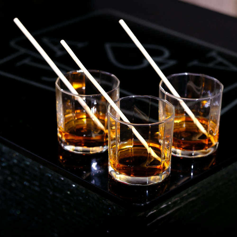 three glasses of whiskey are lined up on a tray