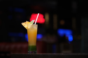 A bartender pouring a layered mocktail into a tall glass