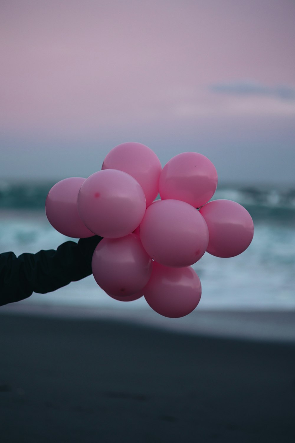 a person holding a bunch of pink balloons