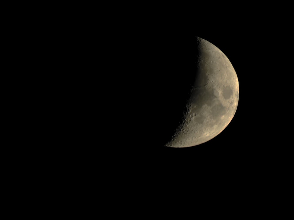 a half moon is seen in the dark sky