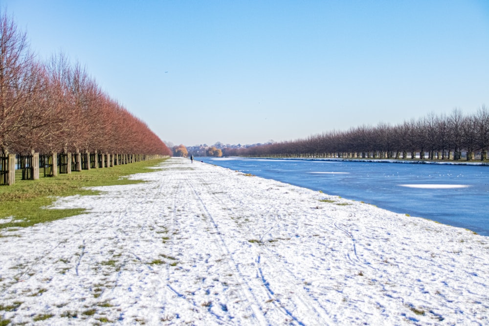 a man walking down a snow covered path next to a river