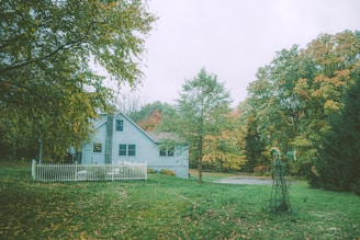 A cozy family home with a white picket fence and a green lawn.