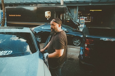 a man standing next to a parked car in a parking lot